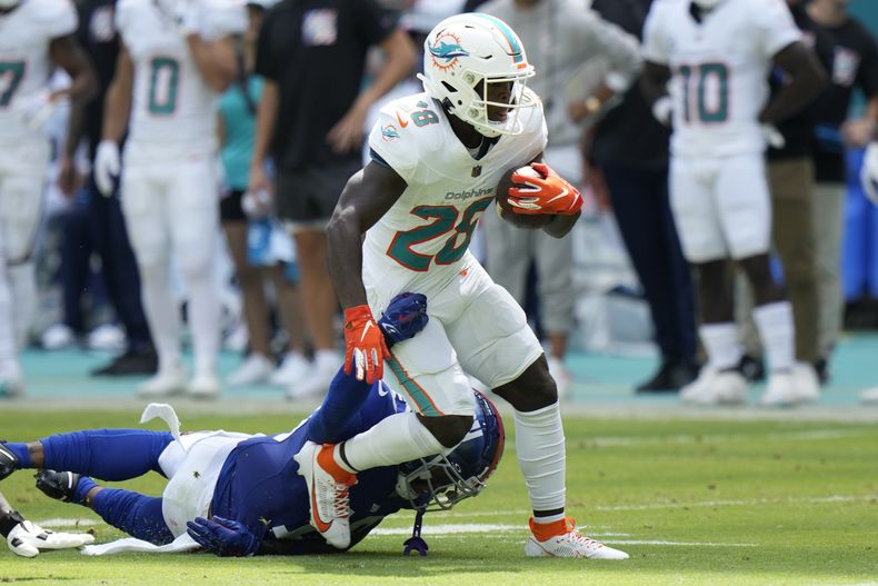DeVon Achane, corredor de los Dolphins de Miami, trata de escapar de Isaiah Simmons, de los Giants de Nueva York, en el partido del domingo 8 de octubre de 2023 (AP Foto/Wilfredo Lee)