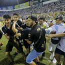 Un grupo de hinchas carga a un aficionado herido hacia la cancha del estadio de Cuscatlán en San Salvador, el sábado 20 de mayo de 2023 (AP Foto/Milton Flores)