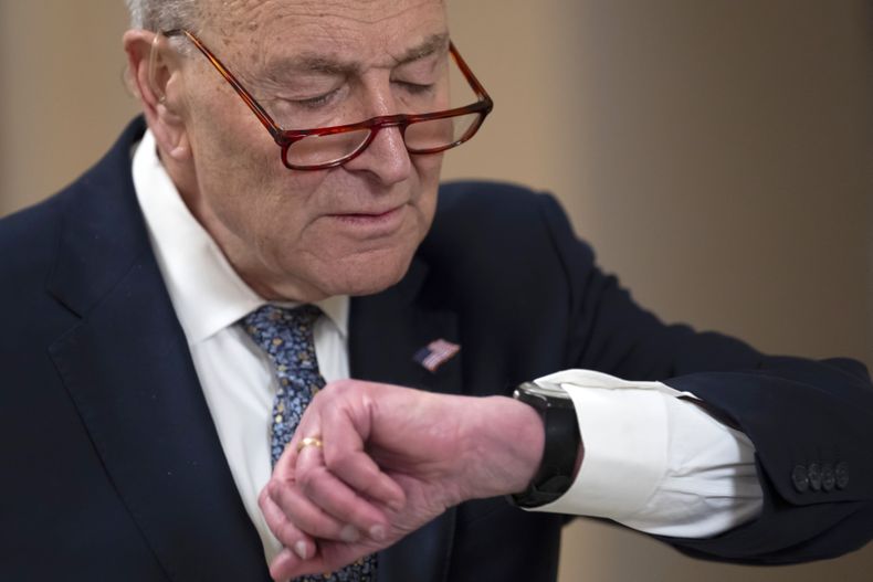 El líder de la minoría en el Senado, Chuck Schumer, revisa su reloj durante una entrevista en el Capitolio, Washington, el viernes 14 de marzo de 2025. (AP Foto/Ben Curtis)