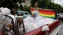ARCHIVO - Con una bandera arcoiris, Wendy Iriepa, va camino de su boda en un auto clásico americano, en La Habana, Cuba, el 13 de agosto de 2011. (AP Foto/Javier Galeano, Archivo)