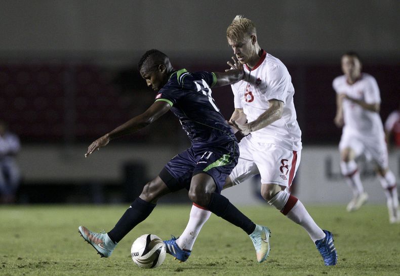 El paname&ntilde;o Armando Cooper hace una gambeta, perseguido por el canadiense Kyle Bekker, durante un partido amistoso disputado el martes 18 de noviembre de 2014 (AP Foto/Arnulfo Franco)