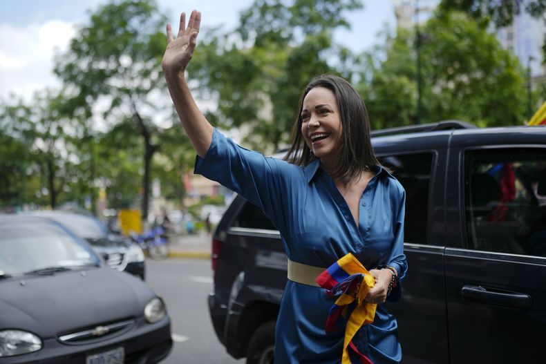 La líder opositora María Corina Machado saluda a sus simpatizantes mientras camina hacia una oficina para inscribirse para participar en las elecciones primarias de la oposición en Caracas, Venezuela, el viernes 23 de junio de 2023. (AP Foto/Ariana Cubillos)