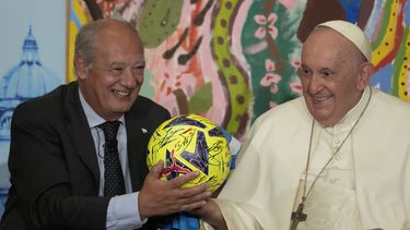 El papa Francisco, acompañado por José María del Corral, presidente de Scholas Occurrentes, sostiene un balón de fútbol que le regalaron en la primera reunión mundial de Ecociudades Educativas, promovida por Scholas Occurrentes, en el Vaticano, 25 de mayo de 2023. (AP Foto/Andrew Medichini)