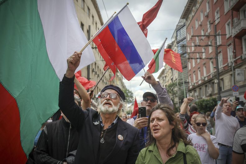 Un manifestante ondea una bandera rusa mientras cientos de búlgaros salen a las calles de Sofía, la capital, y de otras ciudades importantes para protestar contra los planes del gobierno de adoptar el euro y exigir un referendo sobre el tema, en Sofia, el sábado 31 de mayo de 2025. (AP Foto/Valentina Petrova)