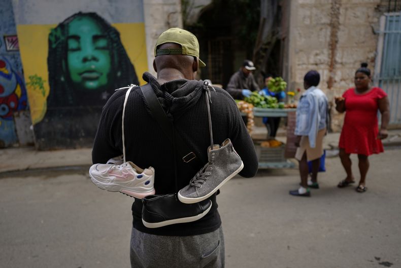 Un vendedor callejero de zapatos busca clientes el miércoles 31 de enero de 2024, en La Habana Vieja, Cuba. (AP Foto/Ramón Espinosa)