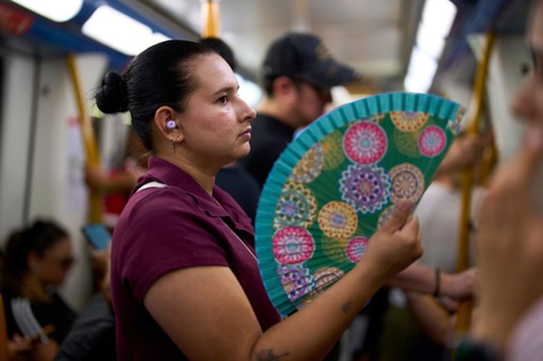 Una mujer se refresca dándose aire con un abanico en el metro, en Madrid, España, el 18 de agosto de 2026. (AP Foto/Manu Fernández)
