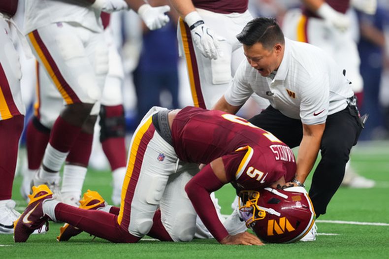 Jayden Daniels (5), quarterback de los Commanders de Washington, reacciona luego de sufrir una lesión en la primera mitad del partido de la NFL en contra de los Cowboys de Dallas, el domingo 20 de septiembre de 2026, en Arlington, Texas. (AP Foto/Julio Cortez)