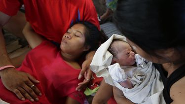 americateve | Una personas sostiene a la reci&eacute;n nacida Bea Joy mientras su madre, Emily Ortega, de 21 a&ntilde;os, descansa tras el parto en una cl&iacute;nica improvisada en el aeropuerto de Tacloban el lunes 11 de noviembre de 2013 en Tacloban, provincia de Le