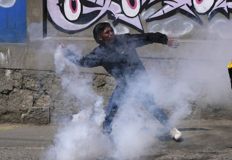 Un conductor de transporte público devuelve un bote de gas lacrimógeno a la policía durante una huelga del transporte público por la escasez de combustible en La Paz, Bolivia, el miércoles 23 de octubre de 2024. (AP Foto/Juan Karita)