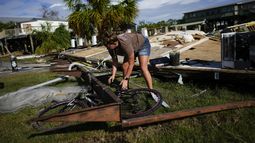 Jessica Long trata de sacar la bicicleta de su sobrina de debajo de un trozo de la vivienda vacacional de la familia, que quedó destrozada por la marejada ciclónica causada por Idalia, en Horseshoe Beach, Florida, el 31 de agosto de 2023, un día después del paso del huracán. (AP Foto/Rebecca Blackwell)