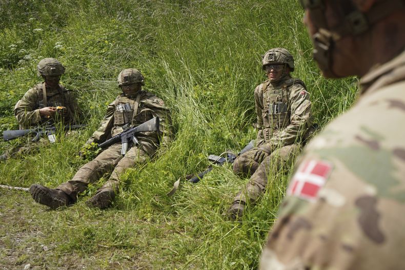 Jóvenes reclutas se sientan esperando en la hierba durante un ejercicio final en un centro de instrucción cerca de los barracones del Real Ejército Danés en Hovelte, 25 kilómetros al norte de Copenhague, Dinamarca, el miércoles 11 de junio de 2025. (AP Foto/James Brooks)