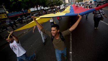 americateve | Estudiantes gritan consignas contra el presidente venezolano Nicol&aacute;s Maduro mientras ondean una bandera nacional, en Caracas, el viernes 25 abril de 2014. (Foto AP/Fernando Llano)