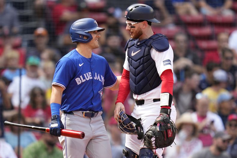 El receptor de los Medias Rojas de Boston, Danny Jansen (derecha), recibe un saludo de Daulton Varsho de los Azulejos de Toronto, quien bateó como emergente por Jansen, durante el resumen del juego de béisbol que fue pospuesto por lluvia en junio, en el Fenway Park el lunes 26 de agosto de 2024. (AP Foto/Charles Krupa)