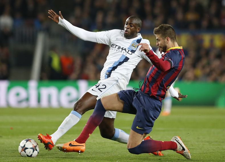 El futbolista de Manchester City Yaya Toure, izq., es enfrentado por Gerard Piqu&eacute;, de Barcelona, durante un partido de la Liga de Campeones el 12 de marzo del 2014 en Barcelona. El club catal&aacute;n dijo el 15 de marzo que Piqu&eacute; y Carl&eac