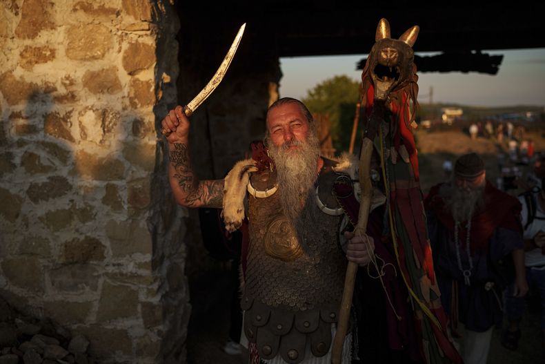 Constantin El Castor Lapusneanu, con un traje de guerrero dacio, alza una espada en Poiana, Rumanía, el sábado 12 de julio de 2025, durante el festival de recreación histórica de Getodava. (AP Foto/Vadim Ghirda)