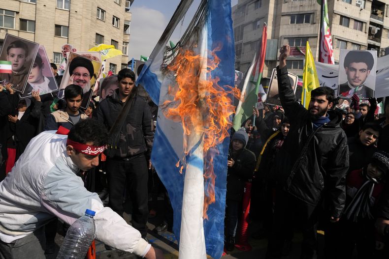 Iraníes queman una bandera israelí al conmemorar el aniversario de la revolución islámica en Teherán el 10 de febrero del 2025. (AP foto/Vahid Salemi)