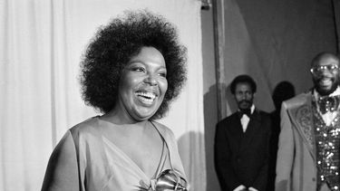 ARCHIVO - Roberta Flack sonríe mientras sostiene el premio Grammy que recibió por su álbum Killing Me Softly With His Song ante la mirada del cantante Isaac Hayes, derecha, en la entrega de los premios Grammy en Los Ángeles, el 4 de marzo de 1974. (AP Foto/Harold Filan, archivo)
