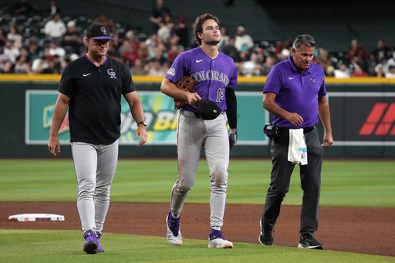 El jugador de los Rockies de Colorado, Kyle Karros (12), abandona el juego tras chocar con Ezequiel Tovar en un batazo conectado por Ketel Marte, de los Diamondbacks de Arizona, en la sexta entrada de un partido de béisbol, el martes 11 de agosto de 2026, en Phoenix. (Foto AP/Rick Scuteri)