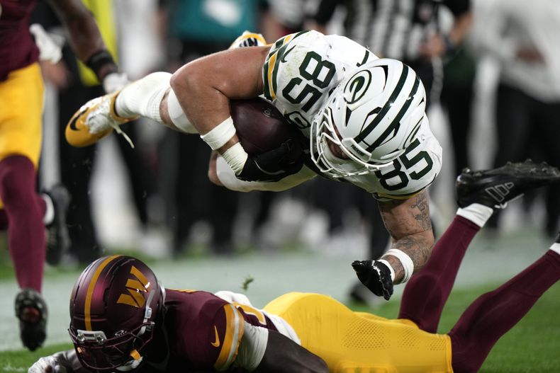 Tucker Kraft, de los Packers de Green Bay, salta encima de Quan Martin, safety de los Commanders de Washington, en el partido del jueves 11 de septiembre de 2025 (AP Foto/Morry Gash)