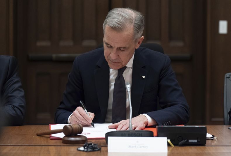 El primer ministro de Canadá, Mark Carney, firma un documento durante una reunión del gabinete en Parliament Hill, el viernes 14 de marzo de 2025 en Ottawa. (Adrian Wyld/The Canadian Press via AP)