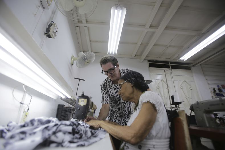 Mario Freixas, propietario de un taller de ropa de alta costura y diseñador de vestuario, junto a una de sus costureras en su taller en La Habana, Cuba, el martes 14 de mayo de 2024. Es una prenda importante, que nos identifica. Cuando se piensa en Cuba se piensa en la guayabera, el tabaco y la palma real”, dijo Freixas. (Foto AP/Ariel Ley)