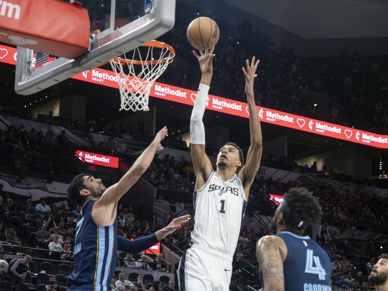 El alero de los Spurs de San Antonio Victor Wembanyama lanza el balón frente al base Jordan Goodwin y el alero Santi Aldama de los Grizzlies de Memphis en el encuentro del viernes 22 de marzo del 2024. (AP Foto/Michael Thomas)