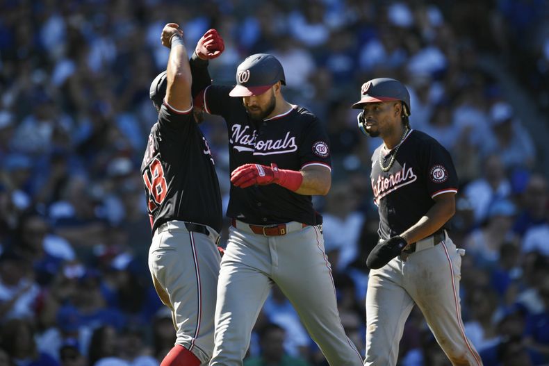 Joey Gallo, de los Nacionales de Washington, celebra con sus compañeros de equipo Juan Yépez, izquierda, y José Tena, derecha, después de conectar un jonrón de tres carreras durante la sexta entrada contra los Cachorros de Chicago en Chicago, el sábado 21 de septiembre de 2024. (AP Foto/Paul Beaty)