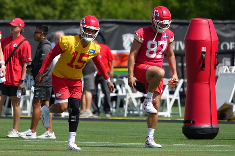 El mariscal de campo de los Chiefs de Kansas City, Patrick Mahomes (15), y el ala cerrada de los Chiefs de Kansas City, Travis Kelce (87), realizan ejercicios de estiramiento durante el entrenamiento del equipo de la NFL el martes 9 de junio de 2026 en Kansas City, Misuri. (Foto AP/Ed Zurga)