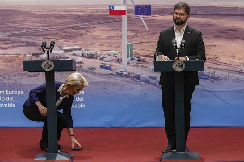 La presidenta de la Comisión Europea, Ursula Von Der Leyen, se agacha para recoger un aparato de traducción mientras se prepara para una conferencia de prensa con el presidente de Chile, Gabriel Boric, en el palacio presidencial de La Moneda en Santiago, Chile, el miércoles 14 de junio de 2023. Una avalancha de críticas ante la decisión de Chile de declinar ser el invitado de honor de la prestigiosa Feria del Libro de Frankfurt, en Alemania, llevó el viernes 16 de junio de 2023 a Boric a tratar de revertir la situación para poder participar. (AP Foto/Esteban Félix)