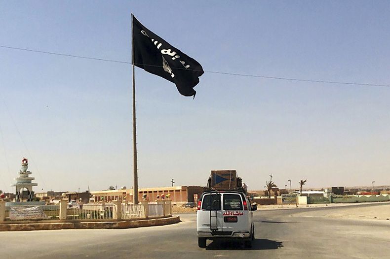 En esta imagen de archivo, un vehículo pasa junto a una bandera del grupo Estado Islámico en el centro de Rawah, una ciudad a 281 kms (175 millas) al noroeste de Bagdad, Irak, el 22 de julio de 2014. (AP Foto, archivo)