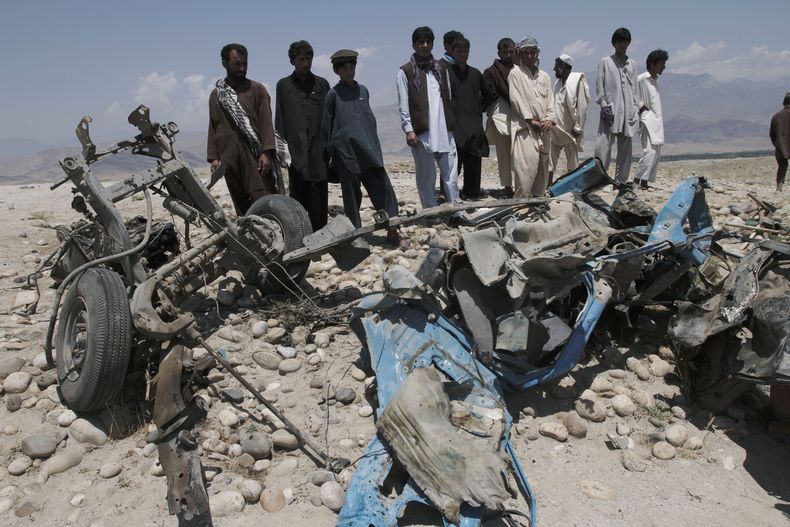 Afganos observan los restos de un veh&iacute;culo destruido por una bomba en un camino en el distrito de Alingar, provincia de Lagham, al este de Kabul,en Afganist&aacute;n, el lunes 3 de junio de 2013. El domingo 9 de febrero, una bomba en un camino dejo