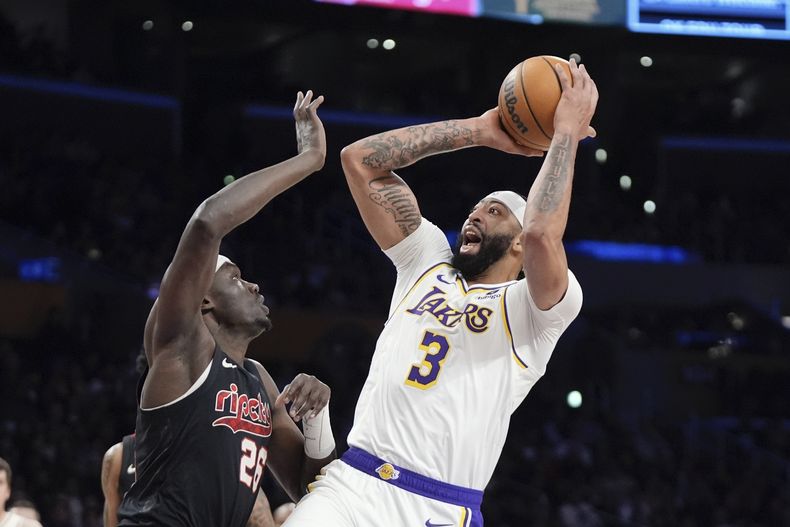 El jugador de los Lakers de Los Ángeles Anthony Davis, a la derecha, tira a canasta mientras el centro de los Trail Blazers de Portland Duop Reath defiende en la primera mitad de su juego de NBA el domingo 21 de enero de 2024 en Los Ángeles. (AP Foto/Mark J. Terrill)