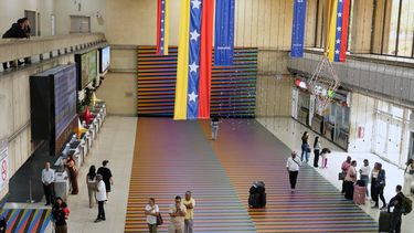 Viajeros esperan en la sala principal del Aeropuerto Internacional Simón Bolívar de Maiquetía, Venezuela, el domingo 13 de noviembre de 2025, después que varias aerolíneas internacionales cancelaran vuelos tras una advertencia de la Administración Federal de Aviación de Estados Unidos sobre una situación peligrosa en el espacio aéreo venezolano. (Foto AP/Ariana Cubillos)