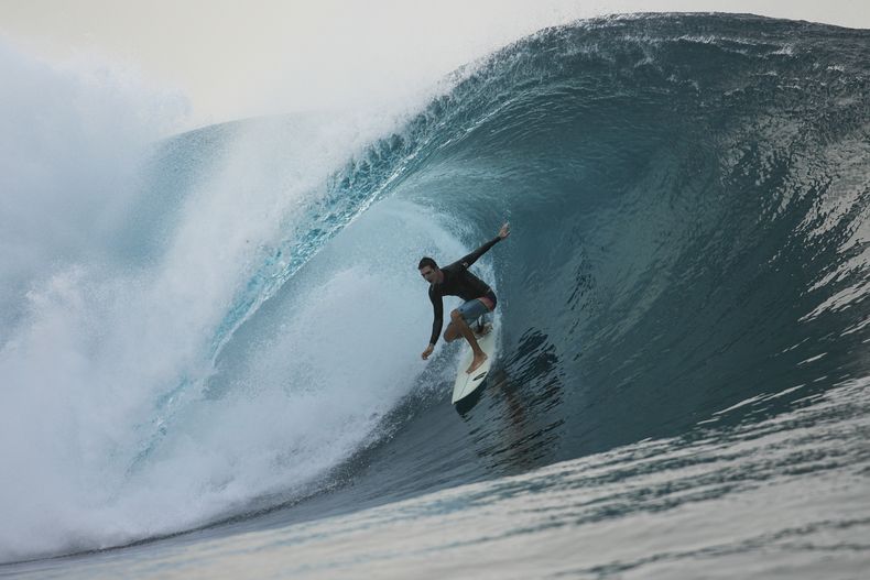 Un surfista se desliza sobre una ola en Teahupoo, Tahití, el sábado 13 de enero de 2024 (AP Foto/Daniel Cole)