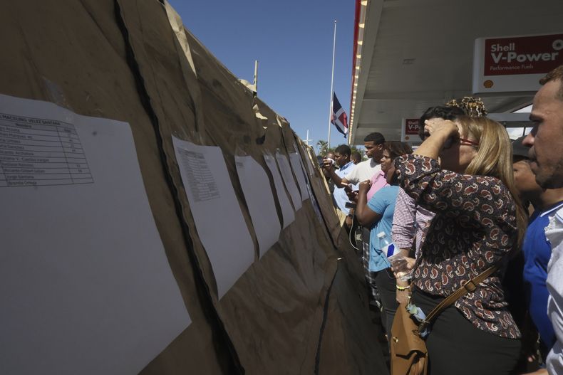 Gente lee las listas de sobrevivientes mientras los equipos buscan a otros atrapados en el club nocturno Jet Set después de que su techo se derrumbara durante un concierto de merengue en Santo Domingo, República Dominicana, el martes 8 de abril de 2025. (AP Foto/Ricardo Hernández)