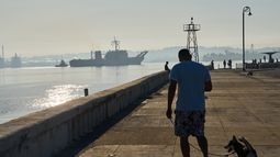 Un hombre pasea a su perro por la Bahía de La Habana, donde el buque Papaloapan de la Armada de México llega a Cuba, el jueves 12 de febrero de 2026. (AP Foto/Ramón Espinosa)