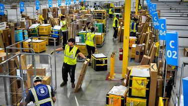 ARCHIVO - Empleados de Amazon cargan paquetes en carritos antes de ponerlos en camiones para su distribución durante el Prime Day de Amazon, en la estación de entrega DAX7 de la compañía, el martes 16 de julio de 2024, en South Gate, California. (AP Foto/Richard Vogel, Archivo)