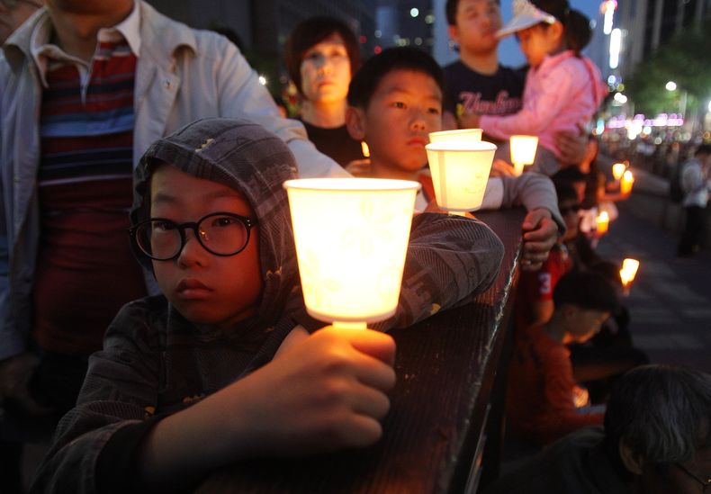 Ni&ntilde;os sostienen velas durante un mitin en homenaje a las v&iacute;ctimas del hundimiento del transbordador Sewol en Se&uacute;l, Corea del Sur, el s&aacute;bado 10 de mayo de 2014. El gobierno de ese pa&iacute;s anunci&oacute; el jueves 15 de mayo