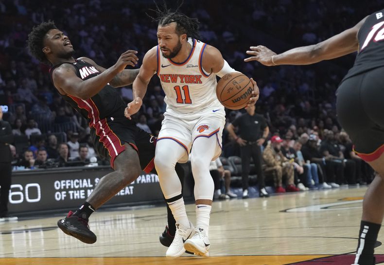 El escolta del Heat de Miami, Davion Mitchell, a la izquierda, recibe una falta del escolta de los Knicks de Nueva York, Jalen Brunson (11), durante la primera mitad de un partido de baloncesto de la NBA, el domingo 2 de marzo de 2025, en Miami. (AP Foto/Lynne Sladky)