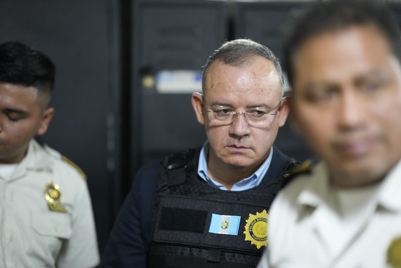 El exministro de Gobernación, Napoleón Barrientos, es escoltado por la policía mientras espera su audiencia en la corte de la Ciudad de Guatemala, el jueves 11 de enero de 2024. Barrientos fue arrestado el jueves por supuestamente no cumplir con sus deberes cuando optó por dialogar con los manifestantes en lugar de utilizar fuerza para expulsarlos como había ordenado un tribunal. (Foto AP/Moisés Castillo)