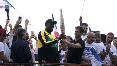 Tony Estanguet (derecha), el presidente del comité organizador de los Juegos Olímpicos de París 2024, entrega a la antorcha a Usain Bolt, el martes 25 de julio de 2023, en París. (AP Foto/Christophe Ena)