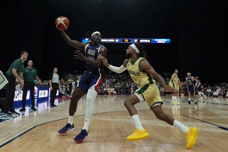 Jrue Holiday, izquierda, de Estados Unidos, y Patty Mills, de Australia, disputan un balón durante el juego de baloncesto de preparación rumbo a los Juegos Olímpicos en Abu Dhabi, Emiratos Árabes Unidos, el lunes 15 de julio de 2024. (AP Foto/Altaf Qadri)