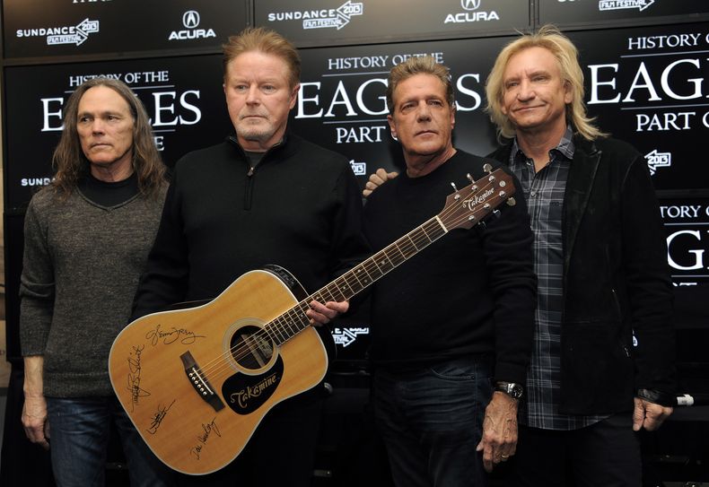 ARCHIVO - Los miembros de Eagles, de izquierda a derecha, Timothy B. Schmit, Don Henley, Glenn Frey y Joe Walsh posan con una guitarra autografiada después de una conferencia de prensa en el Festival de Cine de Sundance, el 19 de enero de 2013, en Park City, Utah. El miércoles 21 de febrero de 2024 inició un juicio penal inusual por la letra escrita a mano del éxito de rock de la banda, Hotel California. (Foto Chris Pizzello/Invision/AP, archivo)