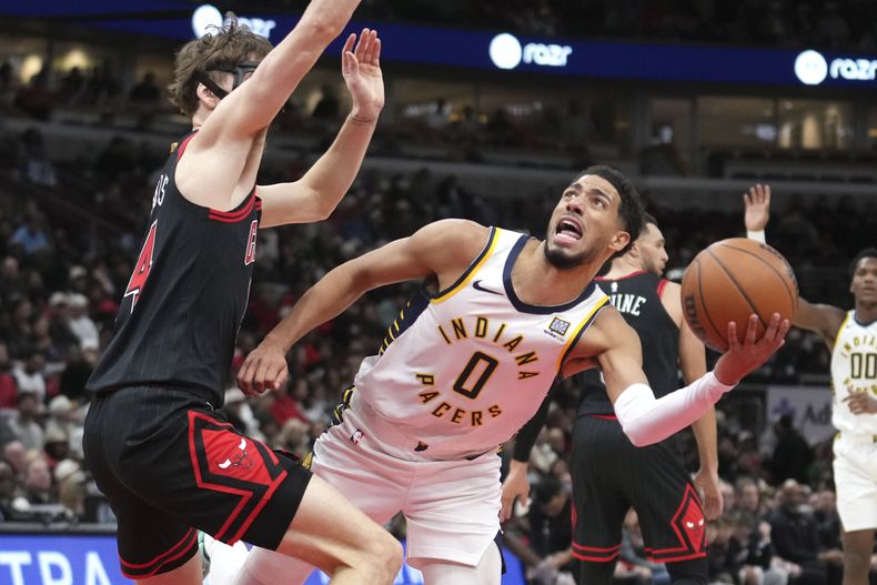 Tyrese Haliburton (0), de los Pacers de Indiana, intenta un tiro a la canasta con Matas Buzelis, de los Bulls de Chicago, ejerciendo labores defensivas durante la segunda mitad del juego de baloncesto de la NBA, el viernes 6 de diciembre de 2024, en Chicago. (AP Foto/Charles Rex Arbogast)