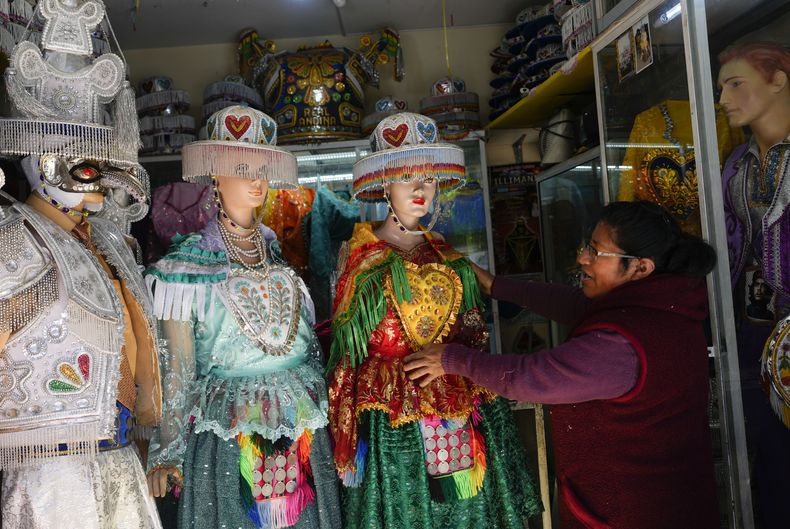 Una costurera ajusta uno de sus vestidos usados por las mujeres que realizan el baile La Llamerada en la próxima Fiesta anual del Señor Jesús del Gran Poder, mientras espera que los bailarines los recojan en una tienda en La Paz, Bolivia, el miércoles 22 de mayo de 2024. La celebración de una semana de duración muestra el folclore andino y comienza el 23 de mayo. (Foto AP/Juan Karita)