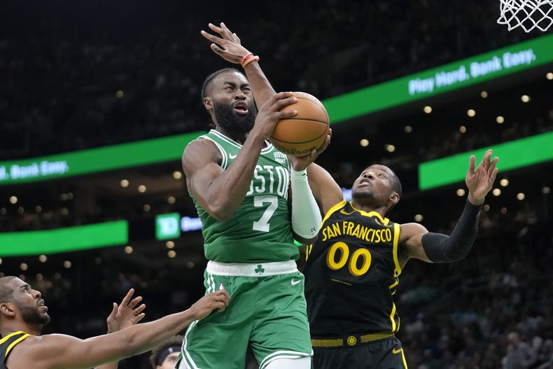 Jaylen Brown (7), de los Celtics de Boston, ataca la canasta mientas Jonathan Kuminga (00), de los Warriors de Golden State, hace labores defensiva durante la segunda mitad del juego de baloncesto de la NBA, el domingo 3 de marzo de 2024, en Boston. (AP Foto/Steven Senne)