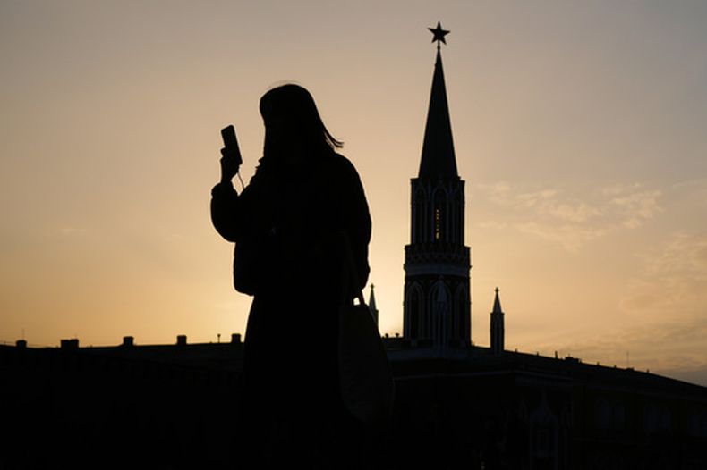 ARCHIVO - Una mujer comprueba su celular mientras camina por la plaza Roja al atardecer, en Moscú, el martes 31 de marzo de 2026. (AP Foto/Pavel Bednyakov, Archivo)