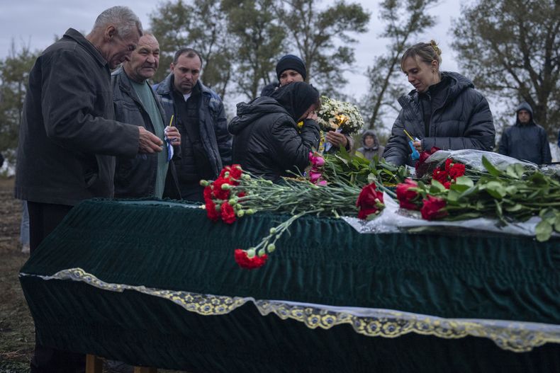 Familiares y amigos lloran junto a los ataúdes de Tetiana Androsovych, de 60 años, y Mykola Androsovych, de 63, asesinados por el impacto de un misil, en un cementerio del pueblo de Hroza, cerca de Kharkiv, Ucrania, el sábado 7 de octubre de 2023. El pueblo ucraniano de Hroza está de luto por el impacto de un misil ruso contra una cafetería del pueblo que mató a más de 50 personas el jueves 5 de octubre. (AP Foto/Alex Babenko)
