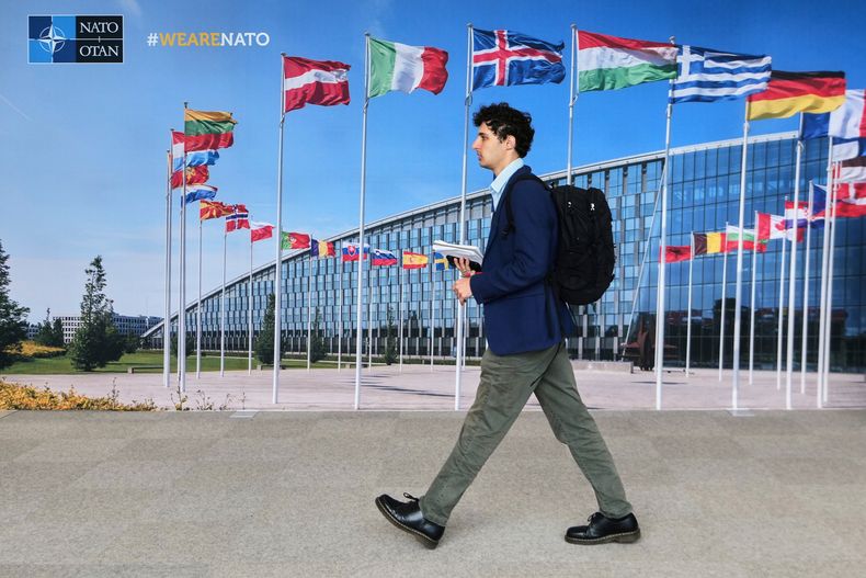 Un hombre camina frente a un mural con banderas de los países miembros de la OTAN, en las oficinas generales de la alianza en Bruselas, el martes 23 de septiembre de 2025. (AP Foto/Virginia Mayo)