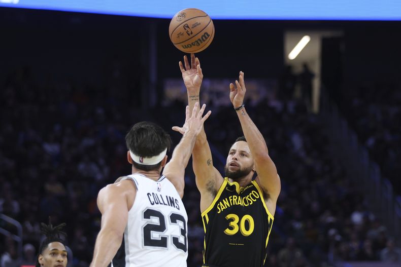 Stephen Curry, base de los Warriors de Golden State, dispara frente a Zach Collins, de los Spurs de San Antonio, durante el partido del viernes 24 de noviembre de 2023 (AP Foto/Jed Jacobsohn)